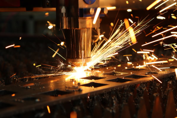 A close-up of a laser cutter in action on a sheet of metal